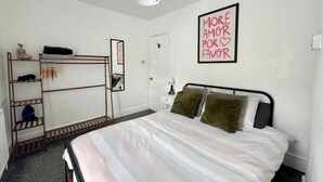 Un dormitorio con cama, armario, espejo y una pared con una cita motivacional.