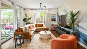 Ein modernes Wohnzimmer mit Ledersofa, rundem Couchtisch und orangenem Akzentstuhl.