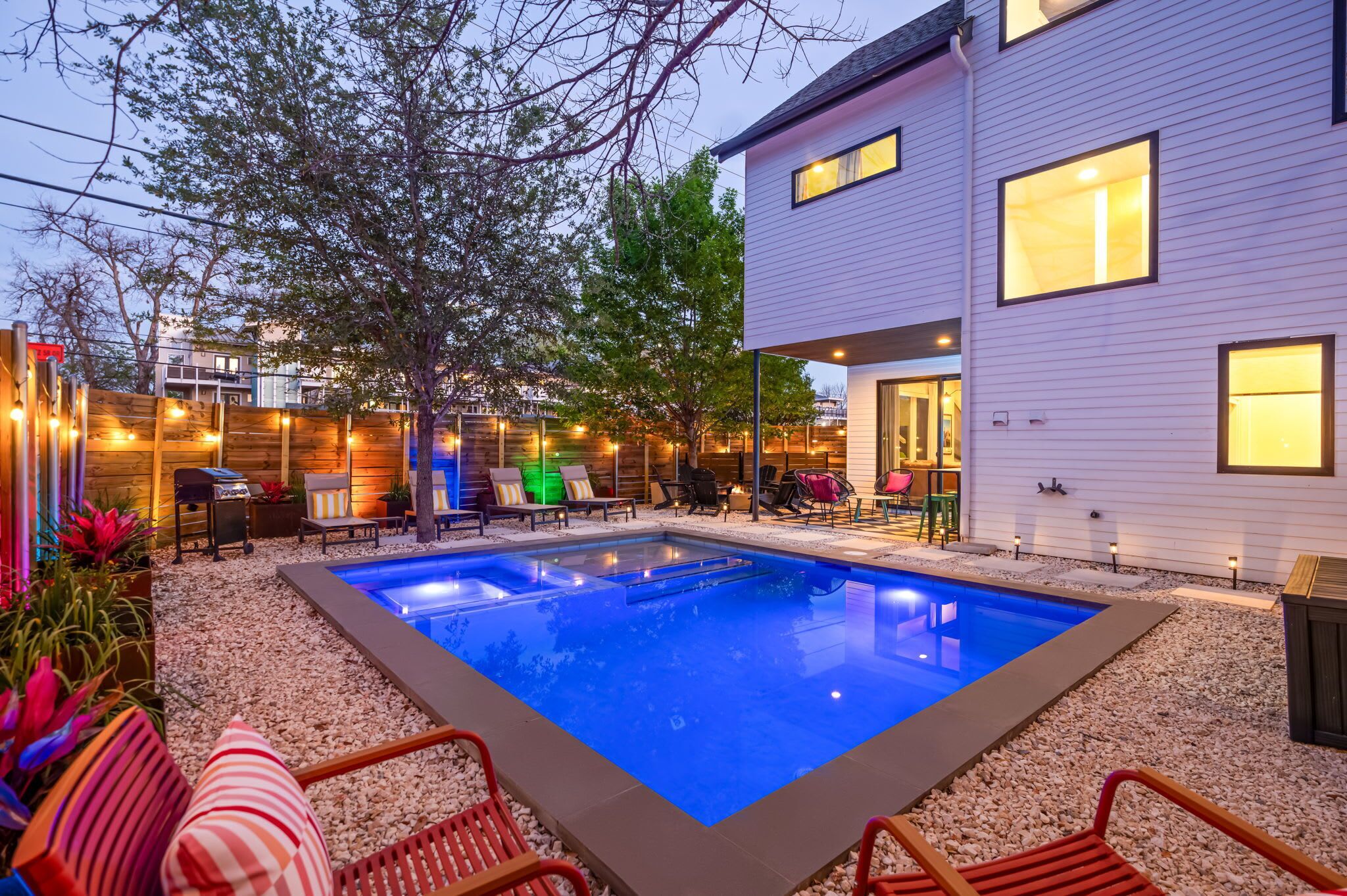 Een modern huis met een zwembad, buitenmeubels en een goed verlicht terras.