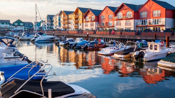 En småbåtshamn med färgglada byggnader och båtar som ligger förtöjda.