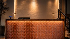 Un comptoir d’accueil au design original, un écran numérique et deux lampes fixées au mur.
