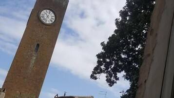 Una torre de ladrillo con un reloj, rodeada de árboles y edificios.