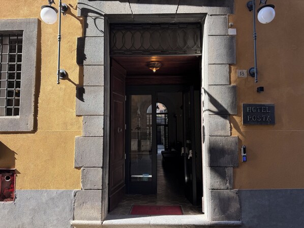 A hotel entrance with a sign reading 'HOTEL POSTA,' a door with a glass panel, and a red mat at the entrance. - Hotel Posta - Palazzo Guidoni (Orvieto)