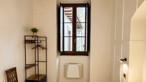 Une chambre d’hôtel avec un lit, une chaise, une armoire, une fenêtre donnant sur un paysage agréable et une table de chevet.