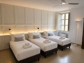 A hotel room with three beds, a ceiling fan, a large window, and a floor lamp. - Hotel Posta - Palazzo Guidoni (Orvieto)
