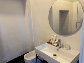 A bathroom with a white sink, a mirror, and a black toilet. - Hotel Posta - Palazzo Guidoni (Orvieto)