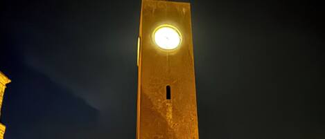 Una torre alta con una luz circular en la parte superior, rodeada de edificios.