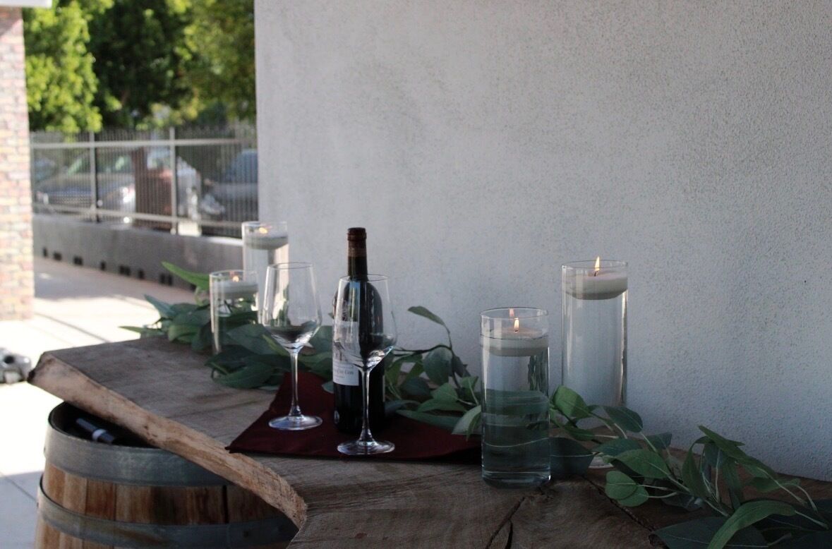 A wooden table with a wine bottle, wine glasses, and candles.