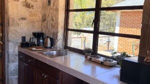 Eine Küche mit Steinwand, einem Fenster mit Aussicht, einem Spülbecken und einer Kaffeemaschine.