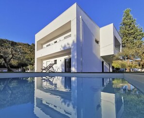 A modern two-story building with a swimming pool in front.