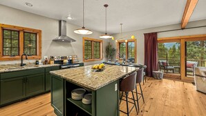 A kitchen with a large island, wooden cabinets, and a view to the outdoors.