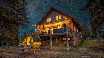 A cabin with a wooden exterior, a balcony, and a barrel.