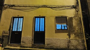 Ein mehrstöckiges Gebäude mit mehreren Fenstern, von denen einige mit Vorhängen versehen sind, und freiliegender Elektroinstallation.