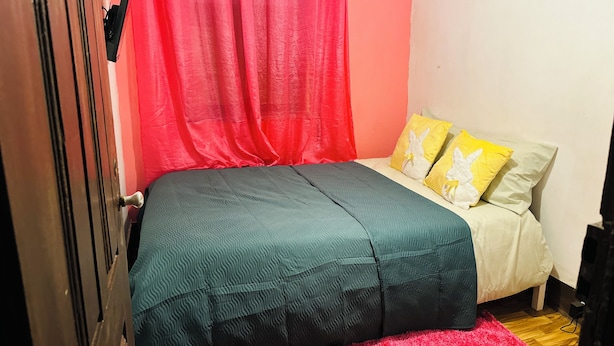 Ein Schlafzimmer mit einem Bett, einem roten Vorhang und einem Fernseher.
