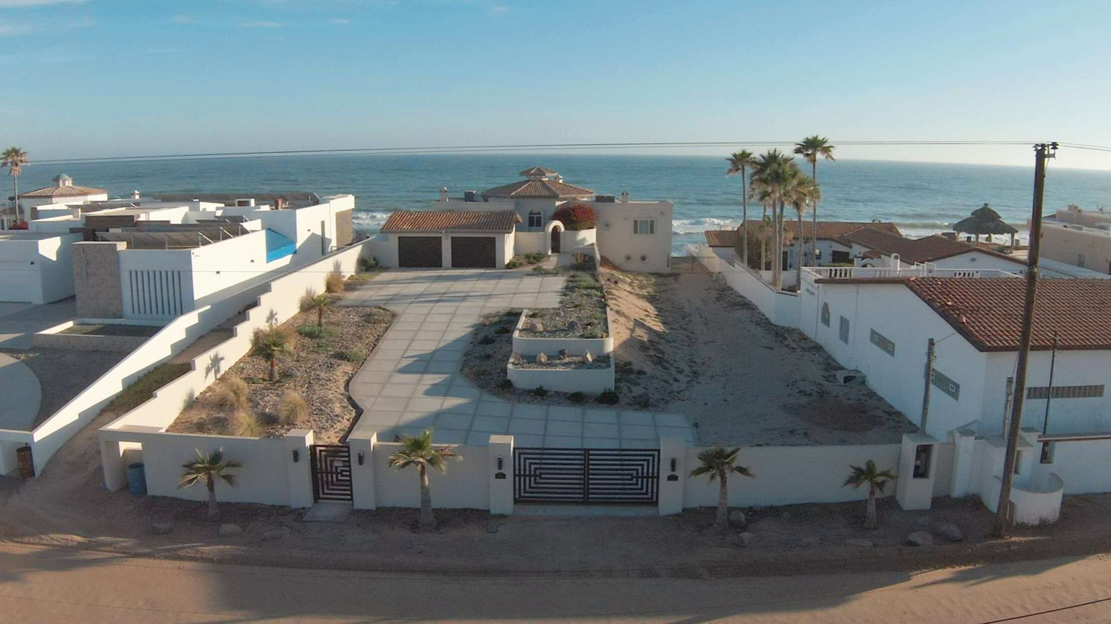 A coastal residential area with houses, a paved driveway, and a view of the ocean.