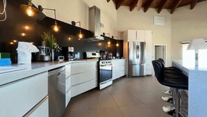 A modern kitchen with a central island, stainless steel appliances, and pendant lighting. - Spacious Family Beachfront Home The Beach House (Puerto Peñasco)