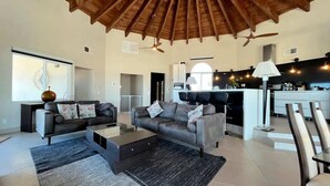 A spacious living area with a high ceiling, a fireplace, and a modern kitchen in the background. - Spacious Family Beachfront Home The Beach House (Puerto Peñasco)