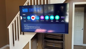 Un téléviseur à écran plat fixé au mur, avec un escalier en arrière-plan.