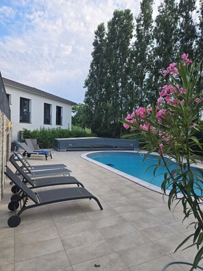 A swimming pool with lounge chairs, a building with windows, and trees in the background. - Large villa with pool for families (Castellare-di-Casinca)