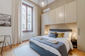 A modern bedroom with a large bed, a radiator, a window with curtains, and a wall-mounted air conditioner. - Quaint 2-bedroom apartment with AC in charming Torino (Torino)
