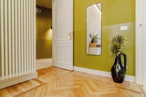 A hallway with a radiator, a white door, a mirror, and a potted plant. - Quaint 2-bedroom apartment with AC in charming Torino (Torino)
