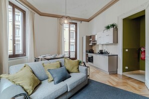 A modern apartment with a grey sofa, kitchen, dining area, and a view of the building. - Quaint 2-bedroom apartment with AC in charming Torino (Torino)