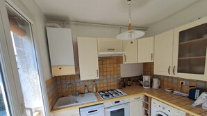 Una cucina compatta con fornello a gas, forno, lavatrice e un piccolo lavandino.