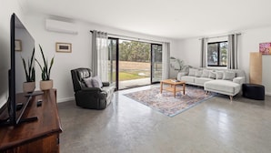Ein geräumiges Wohnzimmer mit Flachbildfernseher, Ledersessel, Sofa und Couchtisch.