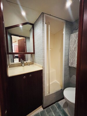 Ein Badezimmer mit Dusche, Toilette, Waschbecken und Spiegel.