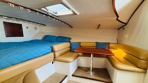 A compact boat interior with a bunk bed, a small table, and a seating area.