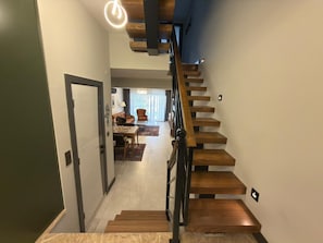 Eine moderne Treppe mit Holzhäuschen und Metallgeländer, die zu einem Essbereich mit Tisch und Stühlen führt.