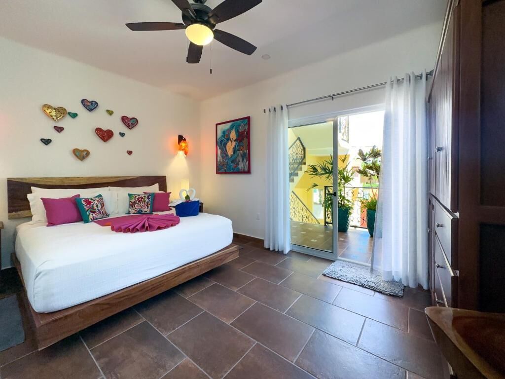 Une chambre à coucher avec un lit, un ventilateur de plafond, des décorations en forme de cœur et un tableau.