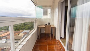 Ein Balkon mit Blick auf die Stadt, ein kleiner Tisch mit Stühlen und ein Fenster mit Aussicht.