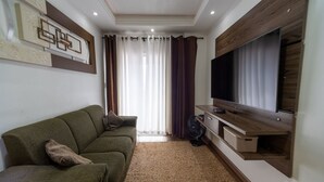 Ein Wohnzimmer mit einer Couch, einem Fernseher und Vorhängen.