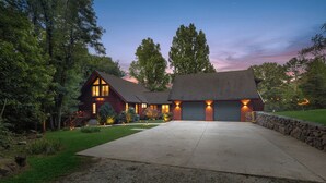 Une maison à deux étages avec des fondations en pierre, une grande allée et un garage.