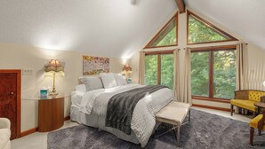 Une chambre à coucher avec un lit, des tables de chevet, une fenêtre et une chaise.