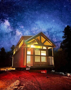 Una baita con cielo stellato, rivestimento in legno e portico illuminato.