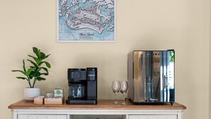 A kitchenette with a coffee maker, two glasses, and a map on the wall.