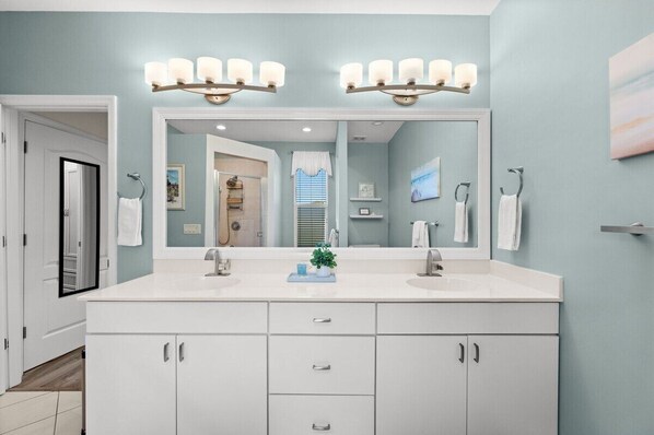 Un baño con un espejo grande, dos lavamanos y un mueble tocador con armarios.