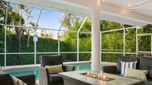 An outdoor patio area with a pool, wicker furniture, and a fire feature.