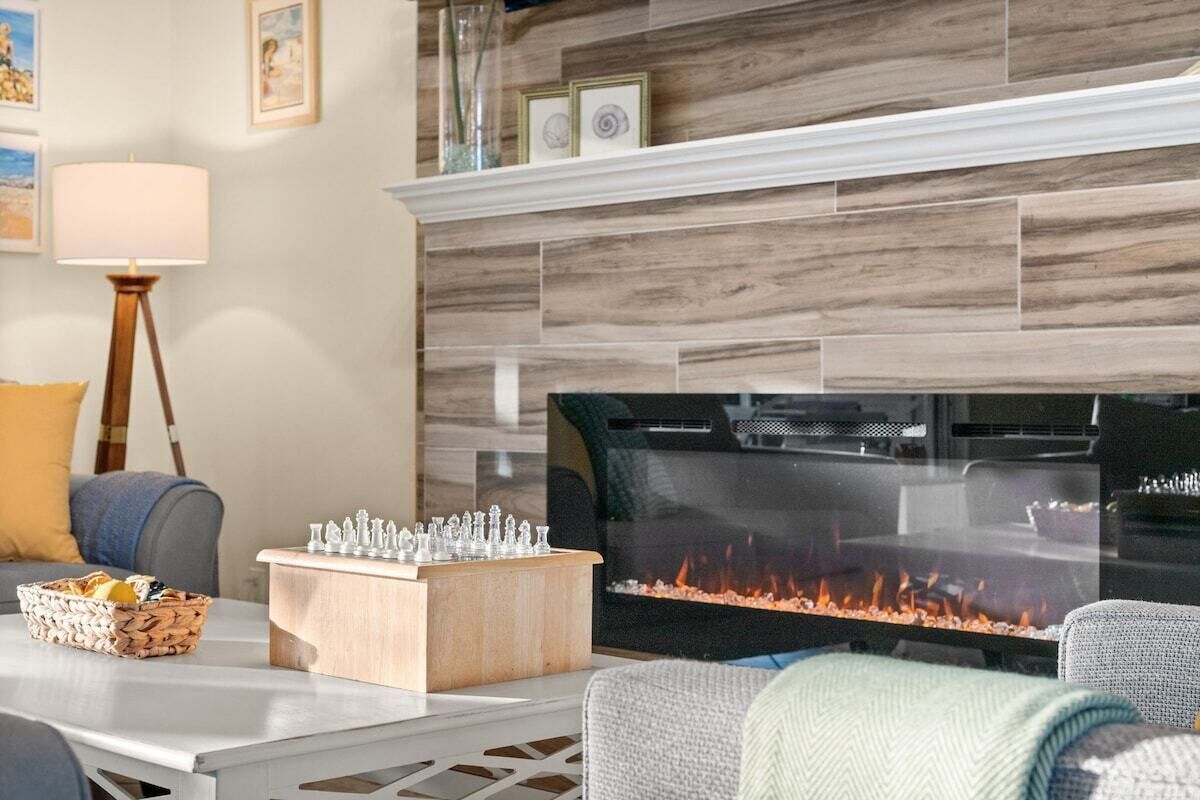 Ein Wohnzimmer mit Kamin, Fernseher, Schachbrett und Lampe.