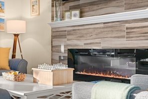 A living room with a fireplace, a TV, a chessboard, and a lamp. - Heated Pool w/ Covered Outdoor Living Near Beach (Marco Island)
