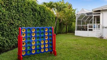 Un jardín con un juego de tablero colorido, una casa blanca y un invernadero.
