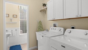 A laundry room with a white washing machine, a dryer, and a shelf above the dryer.