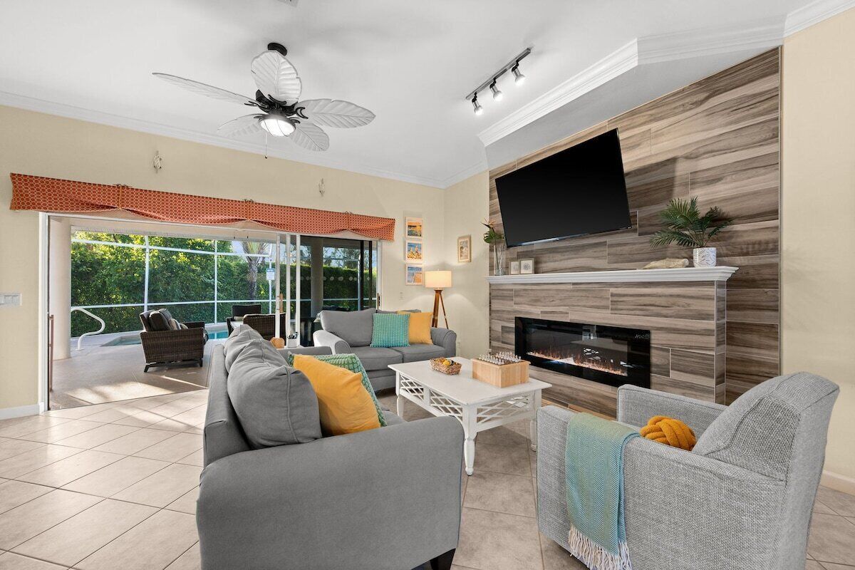 A spacious living room with a fireplace, comfortable seating, and a large TV mounted on the wall.