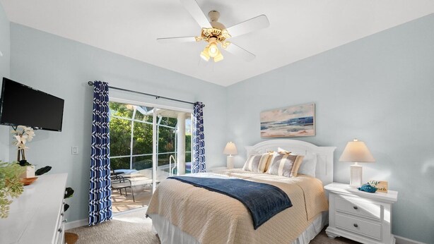 A bedroom with a bed, a television, a desk, and a window with curtains.