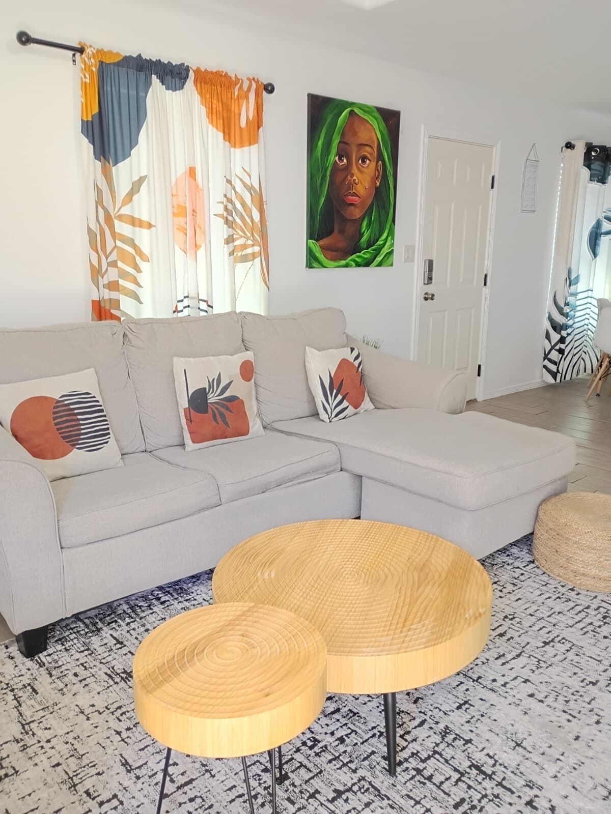 A modern living room with a sectional sofa, round wooden coffee tables, and a large abstract painting on the wall.