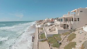 Ein Hotel an der Küste mit Blick auf den Strand, mehreren Balkonen und einer Treppe zum Strand.