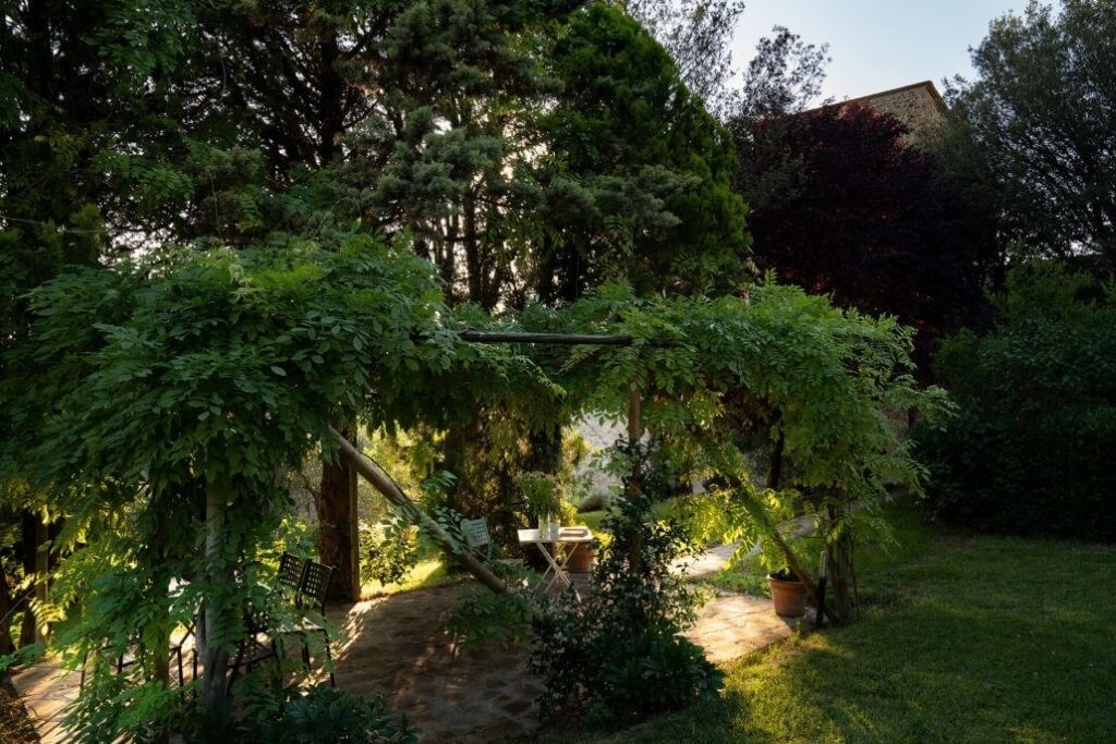 En have med bænk, bord og pergola.