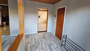 A hallway with wooden flooring, a ceiling fan, and a door leading to a kitchen area. - Sandmo Holiday Home 11 (Ålands landsbygd)